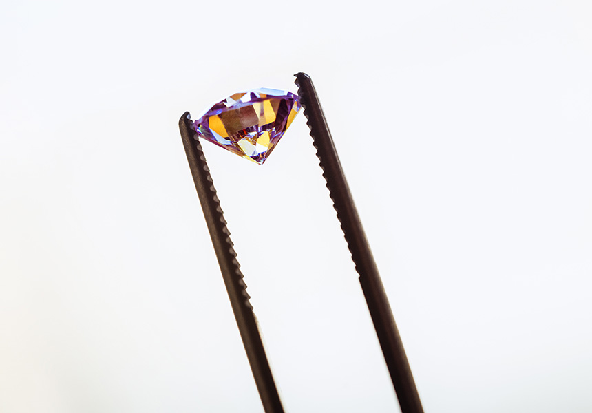 golden gemstone in tweezers