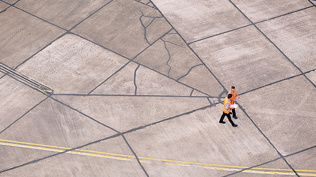 Two men walking together on the street looking at papers