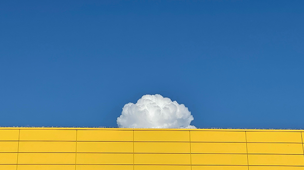 A cloud behind a yellow building in the blue sky